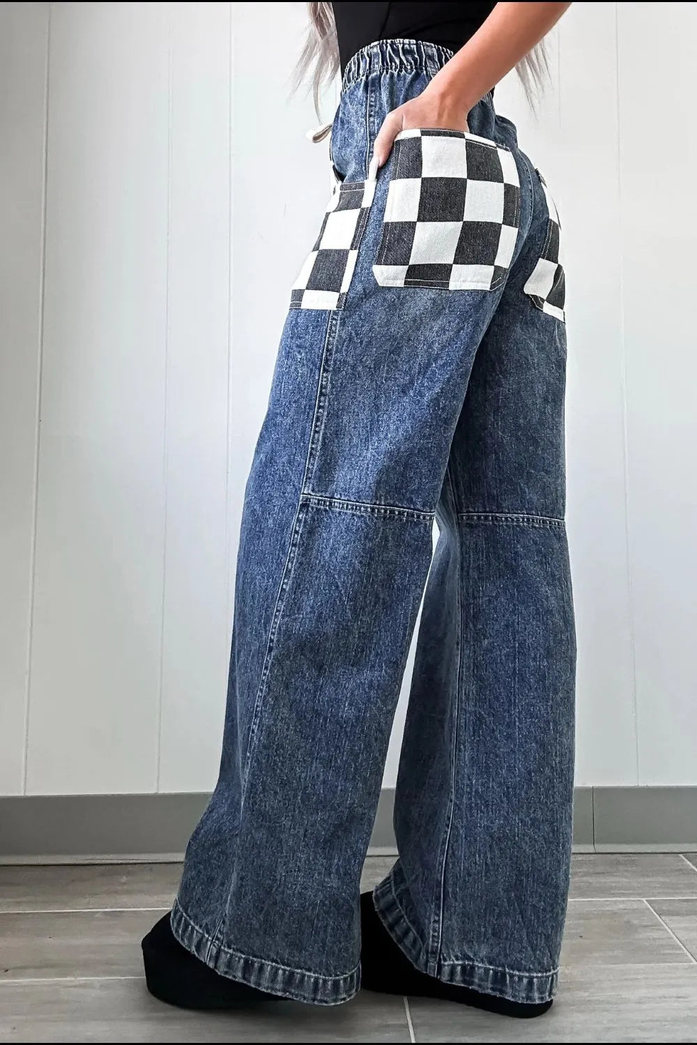 Wide-leg jeans with checkered pocket designs worn by a person.