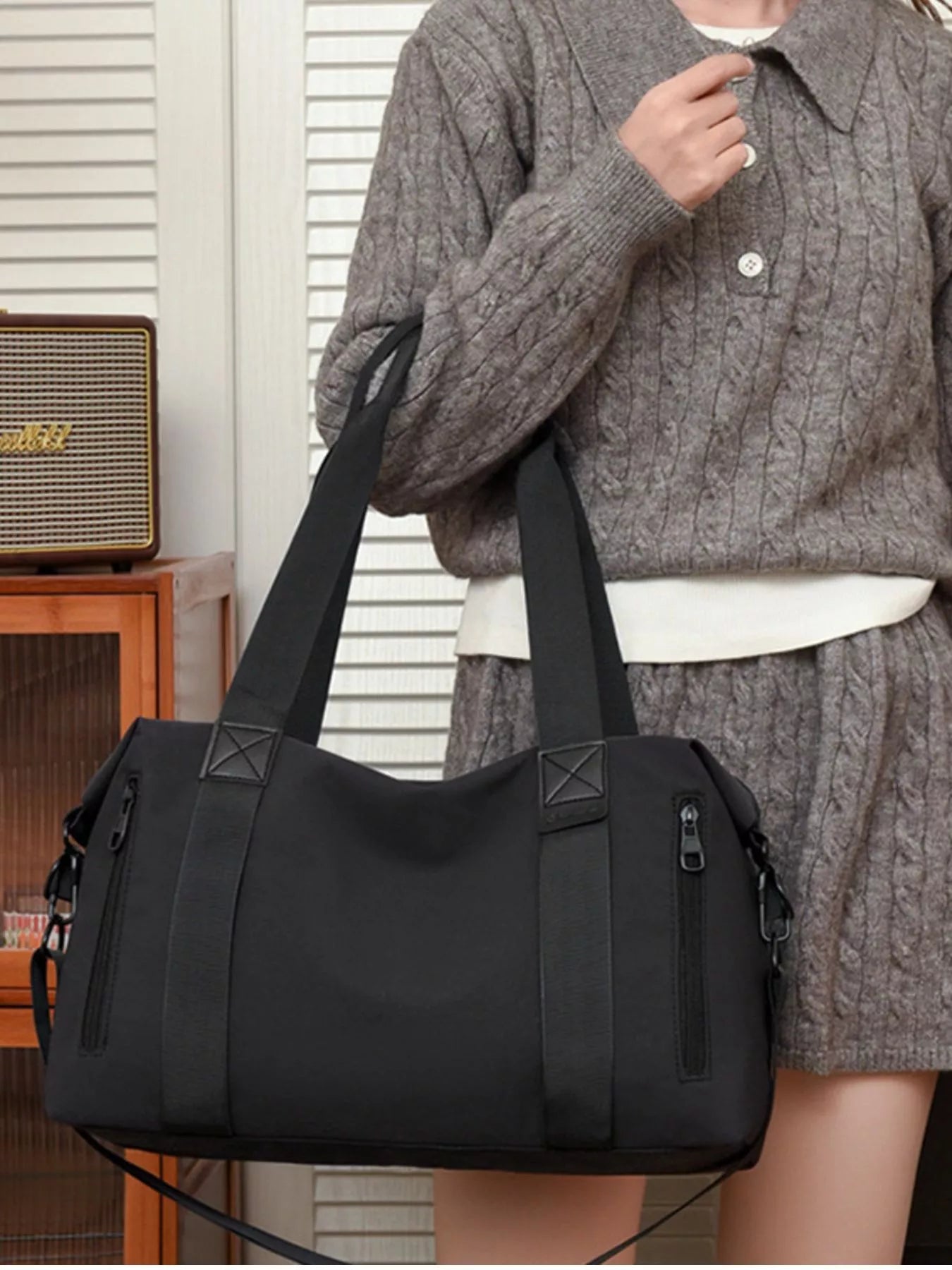 Person holding a black handbag in an indoor setting