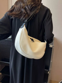 Person wearing a black coat with a white shoulder bag indoors.