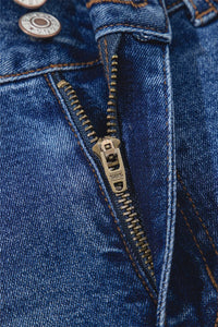 Close-up of a blue denim jacket with a zipper and buttons.