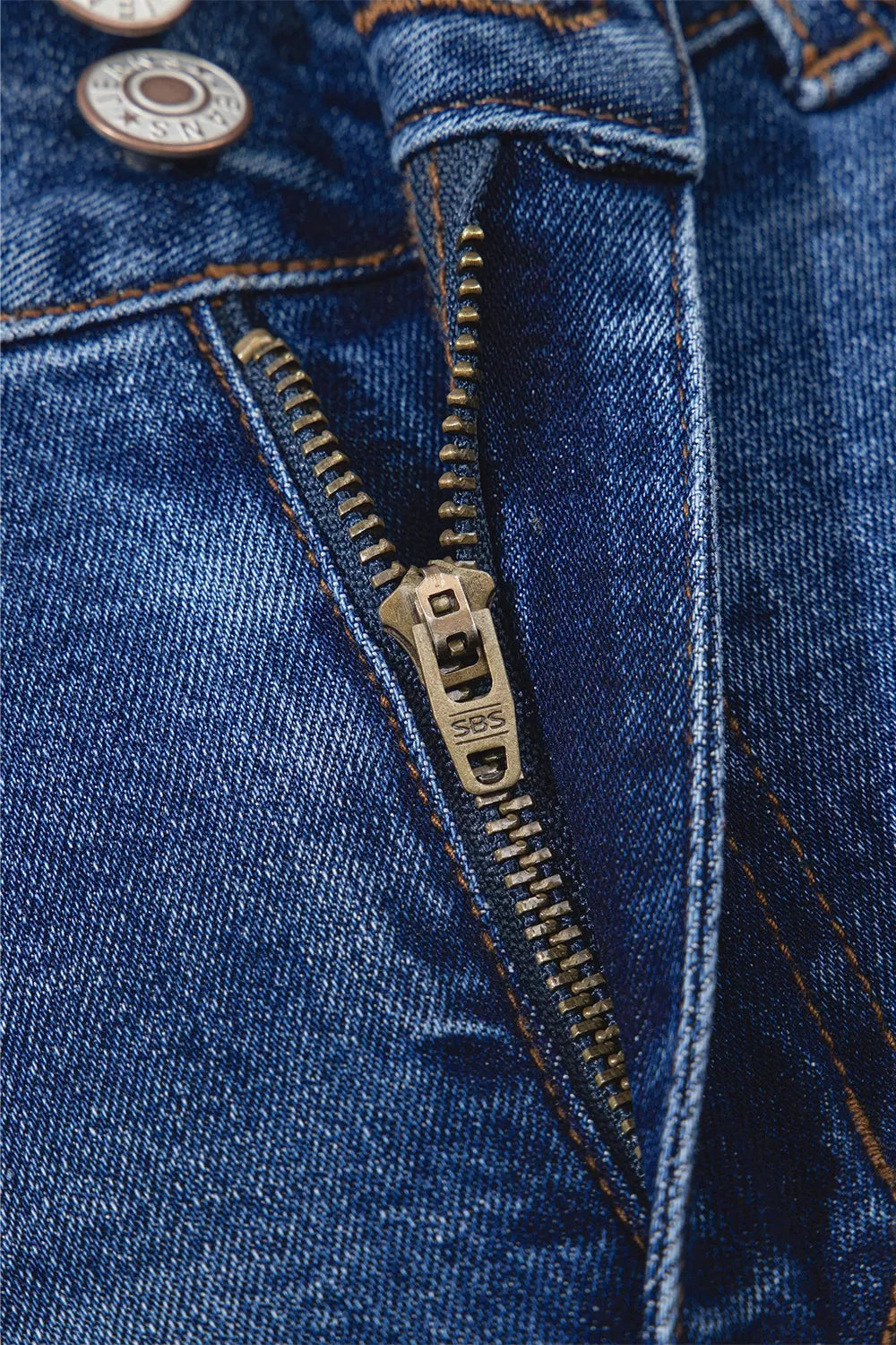 Close-up of a blue denim jacket with a zipper and buttons.