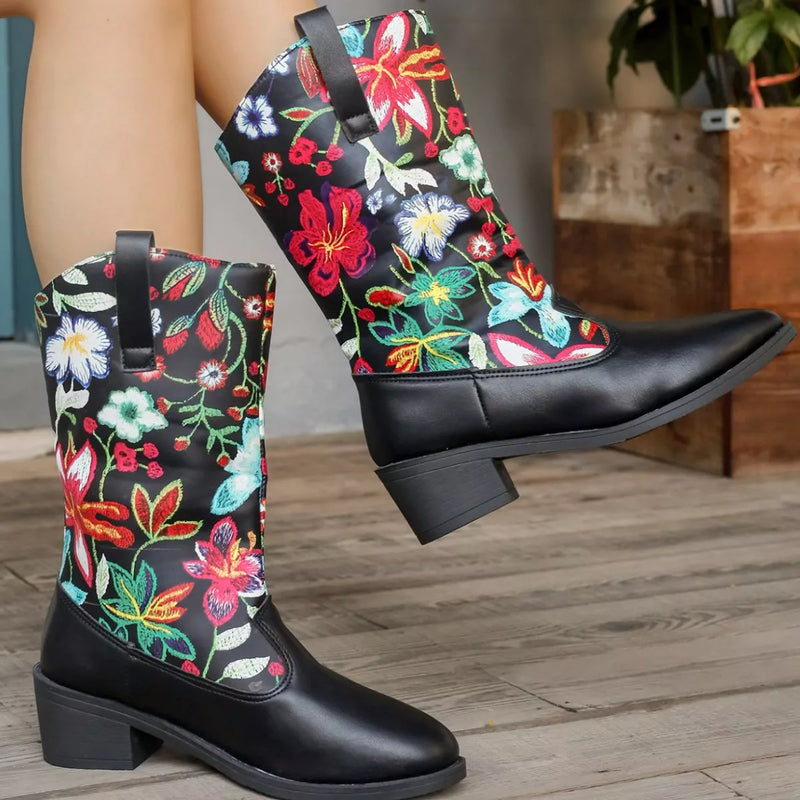Black boots with colorful floral embroidery on a wooden floor.