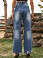 Person wearing blue jeans standing in front of a stone wall.