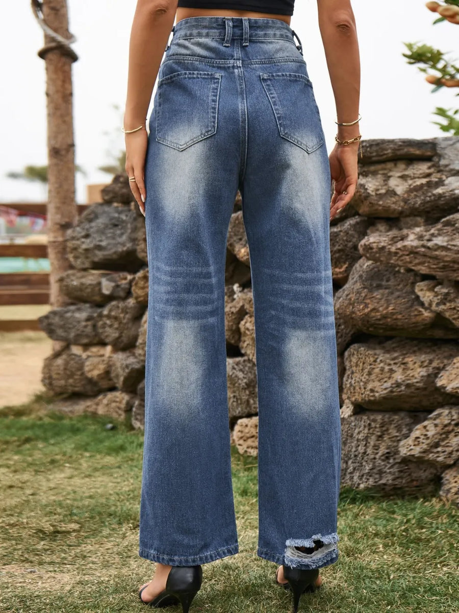 Person wearing blue jeans standing in front of a stone wall.