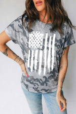 Person wearing a camouflage t-shirt with an American flag design on a plain background