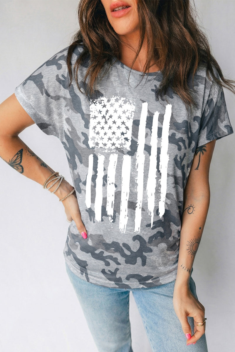 Person wearing a camouflage t-shirt with an American flag design on a plain background