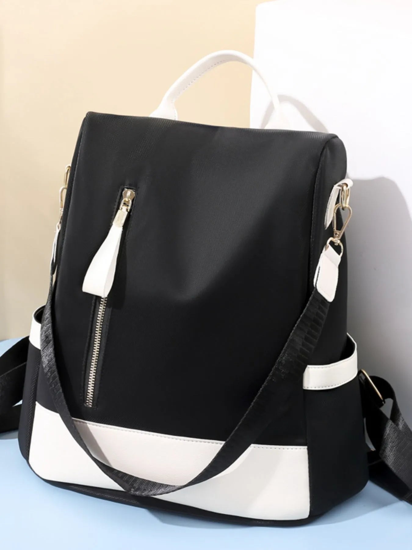 Black and white backpack on a light blue surface with a beige background