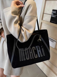Black handbag with 'MORCA' branding held by a person wearing a beige coat.