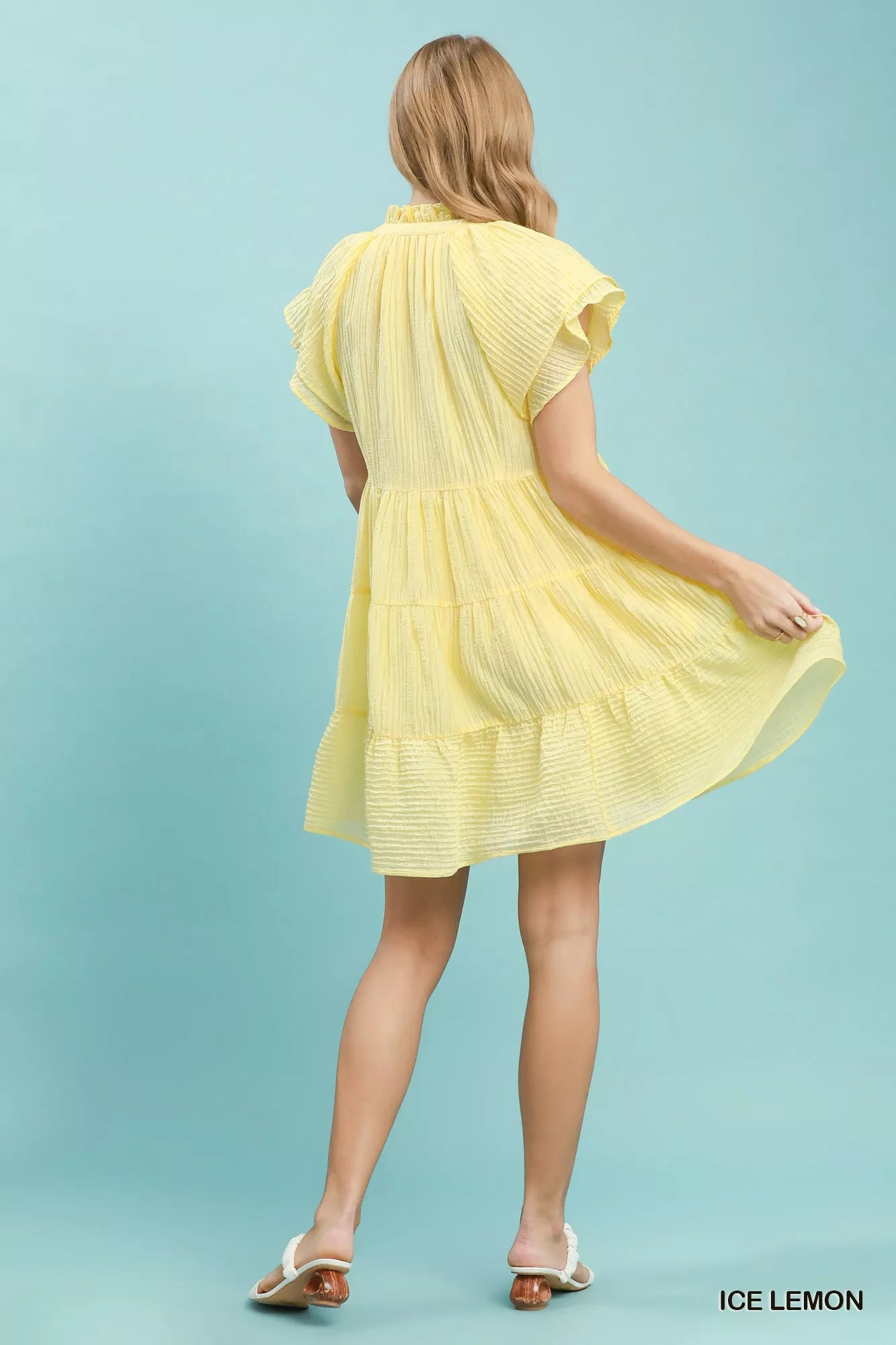 Woman wearing a yellow dress against a light blue background