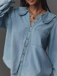 Light blue denim shirt with ruffled collar worn by a person on a dark background