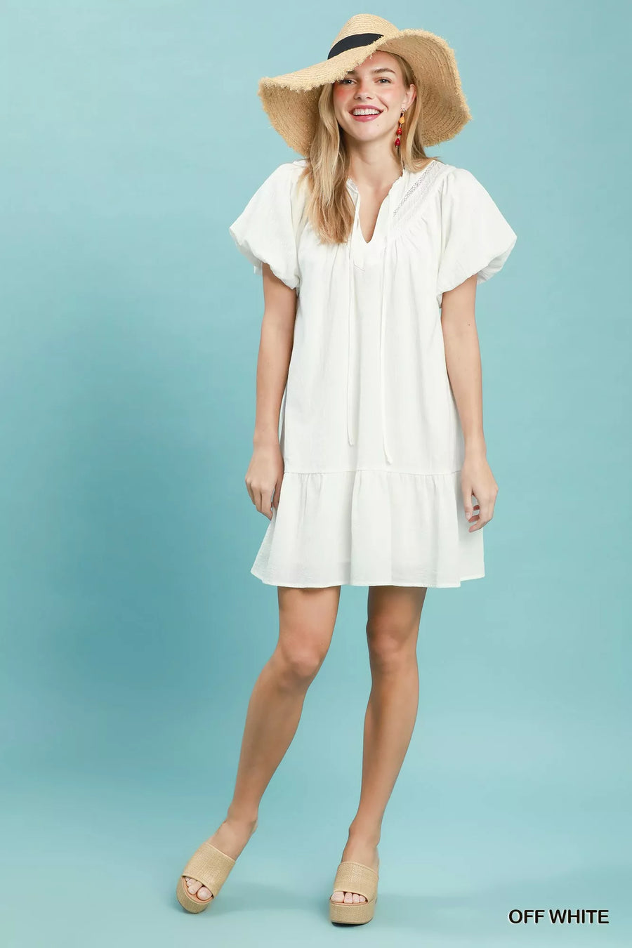 Woman wearing a white dress and wide-brimmed hat on a light blue background