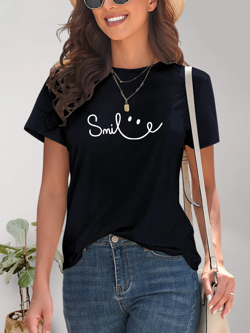 Woman wearing a black t-shirt with 'Smile' text and smiling.