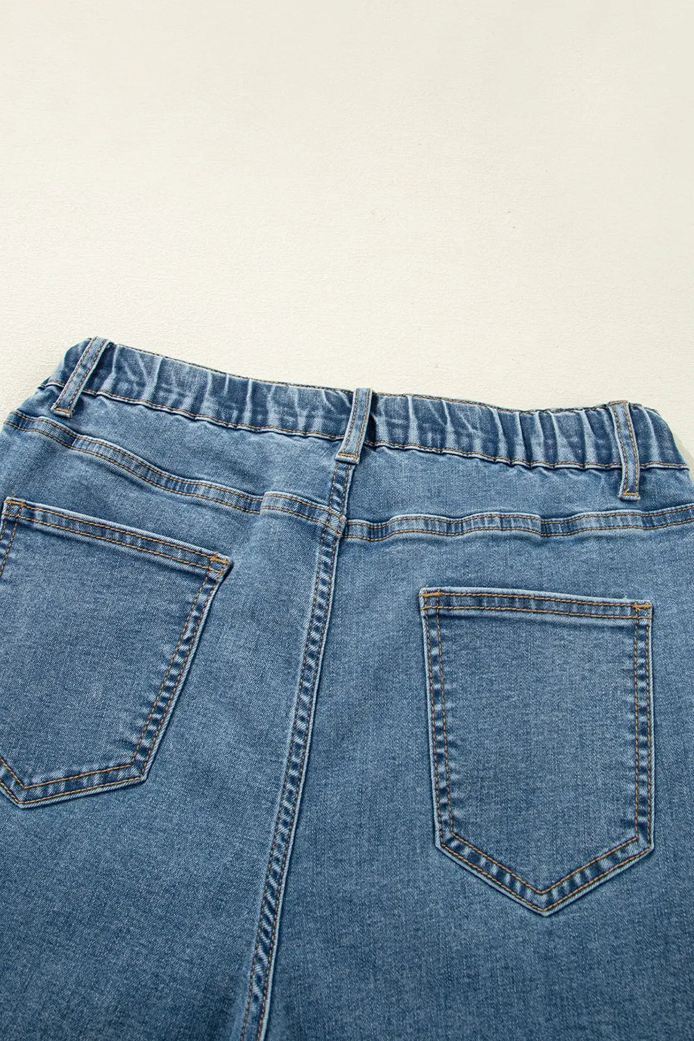 Close-up of blue denim jeans on a beige background