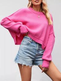 Person wearing a pink sweater and denim shorts on a plain background