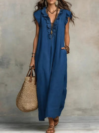 Woman wearing a blue dress holding a straw bag against a neutral background