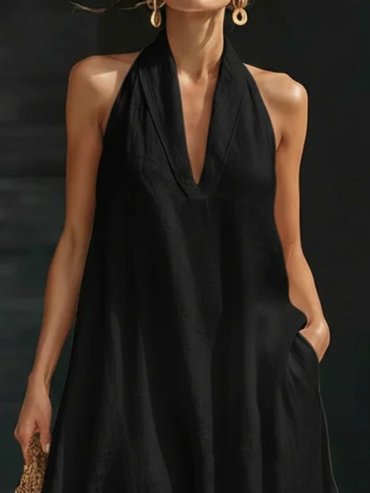 Woman wearing a black halter neck dress against a dark background