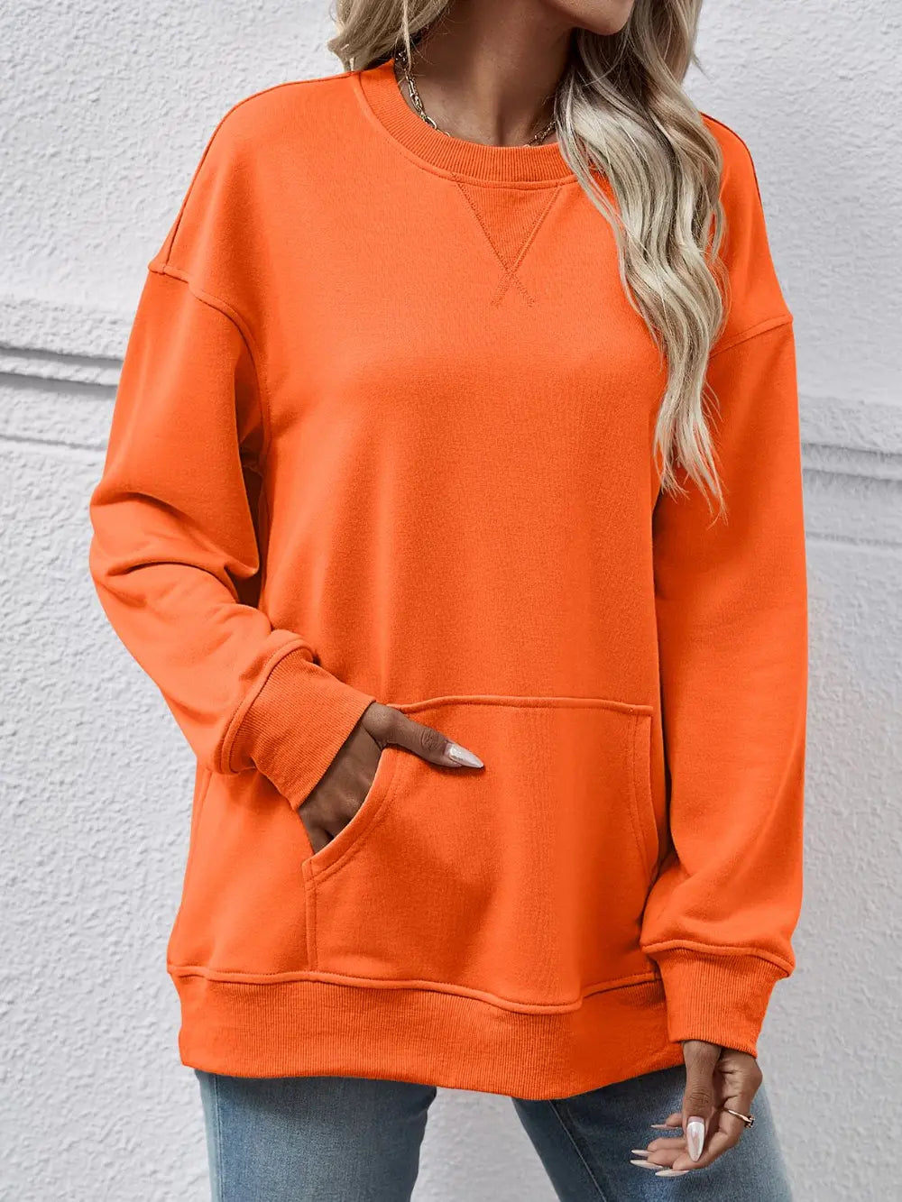 Person wearing an orange sweatshirt against a gray background