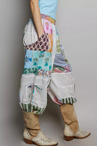 Person wearing colorful patchwork pants with a plain background