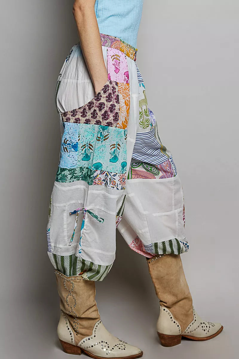 Person wearing colorful patchwork pants with a plain background