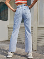 Person wearing light blue jeans and a red and white crop top, standing in front of a building.