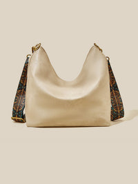 Beige handbag with patterned strap on a beige background
