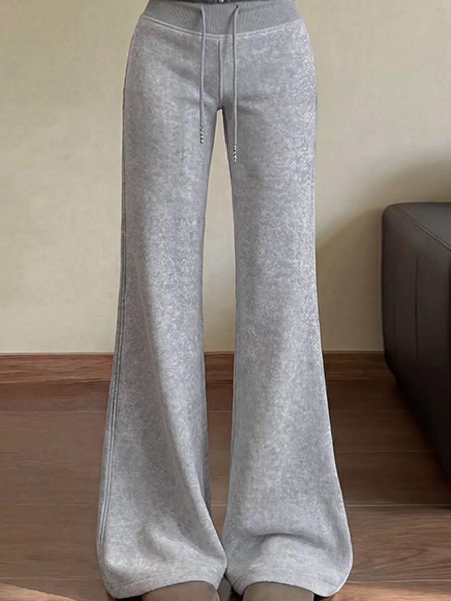 Light gray wide-leg sweatpants with a drawstring waist, shown on a model standing indoors on a wooden floor.