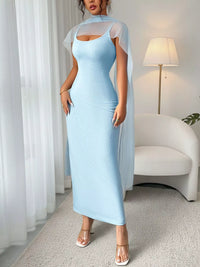 Woman wearing a light blue dress with sheer sleeves in a room with white curtains and a lamp.