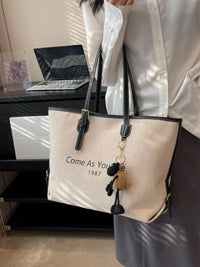 Person holding a beige tote bag with text in an office setting