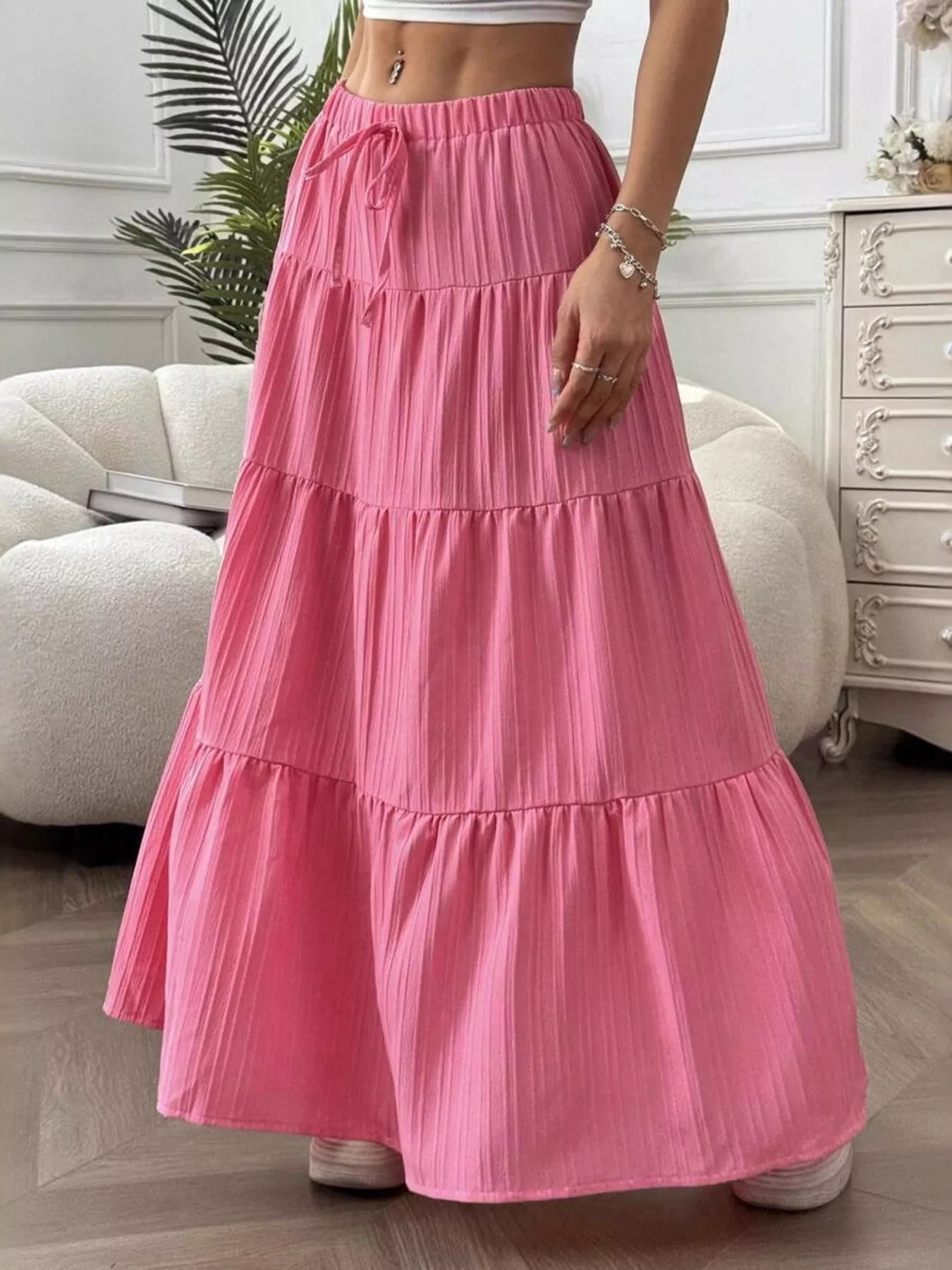 Person wearing a pink tiered skirt in a room with a couch and dresser.