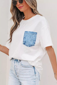 Woman wearing a white t-shirt with a denim pocket design and light blue jeans.