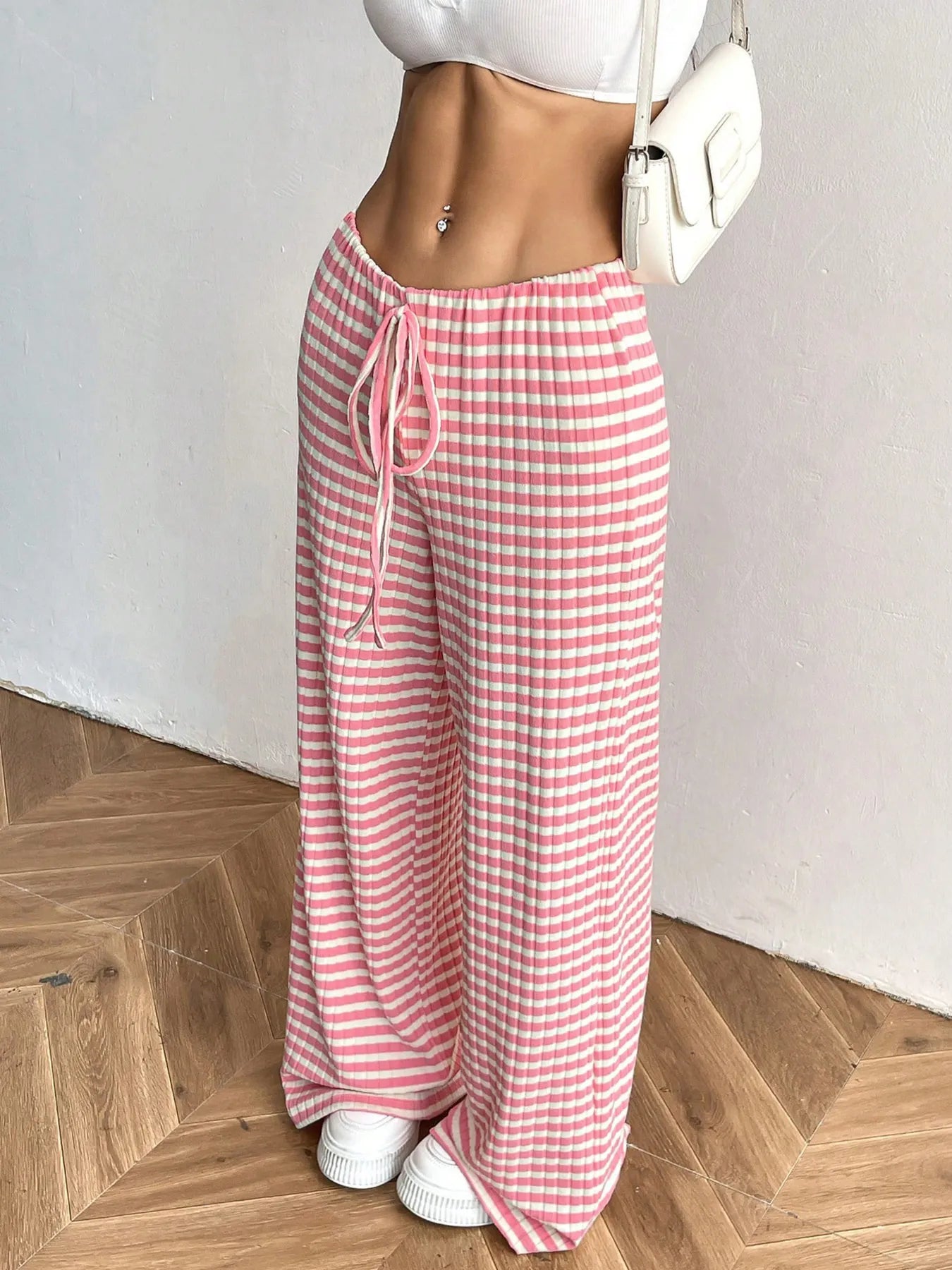 Person wearing pink and white striped pants on a wooden floor.