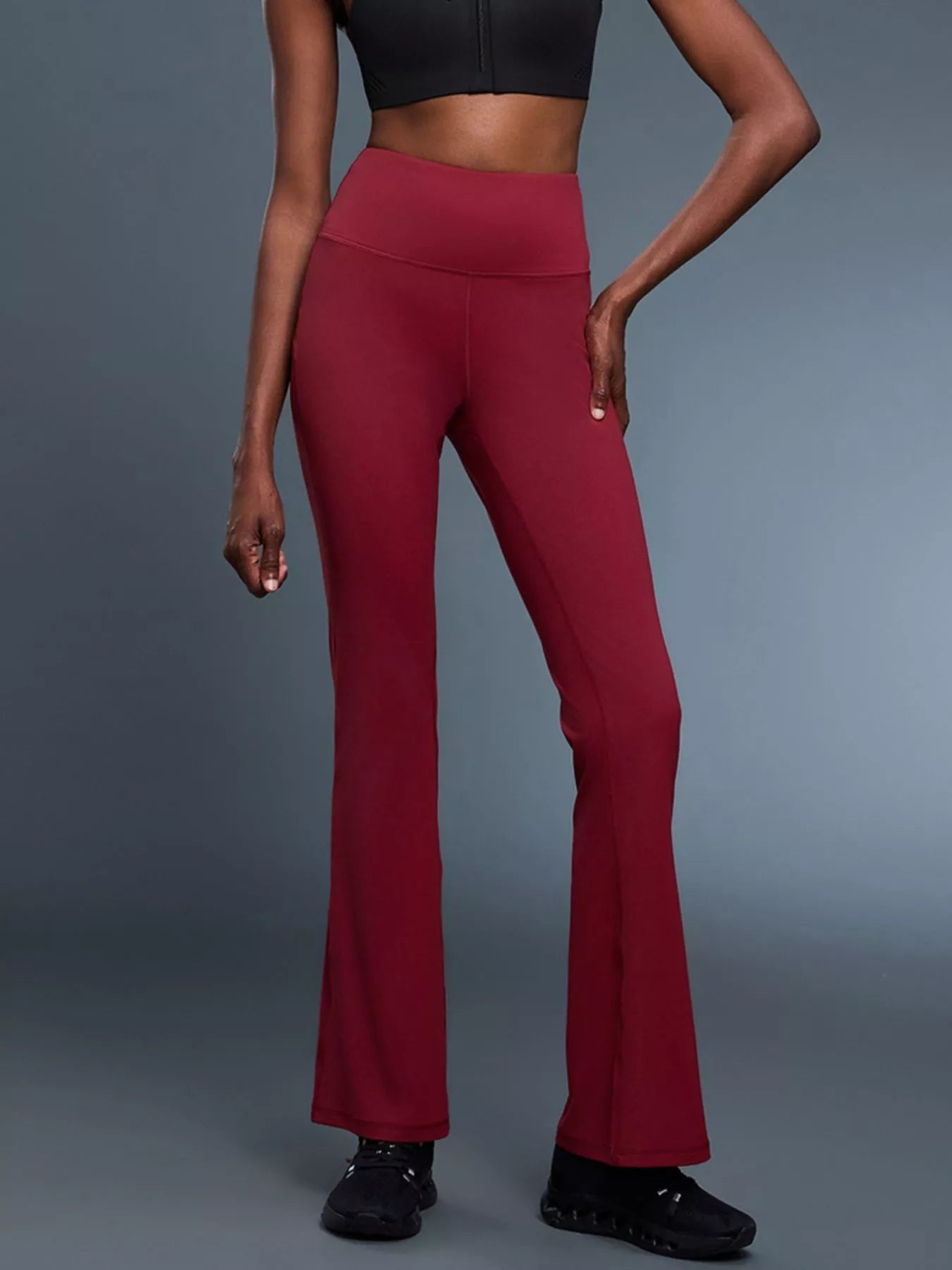 Person wearing red flared pants on a gray background