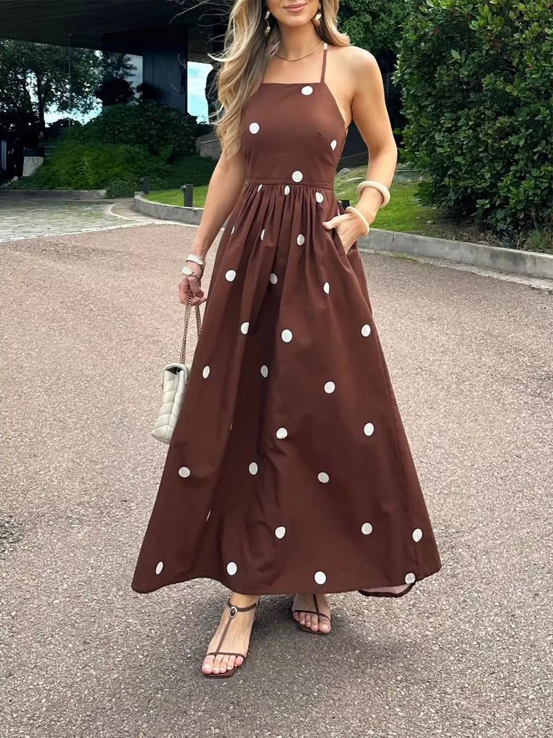 Woman wearing a brown dress with white polka dots standing on a street.