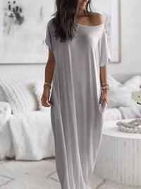 Woman wearing a long gray dress in a minimalistic room.