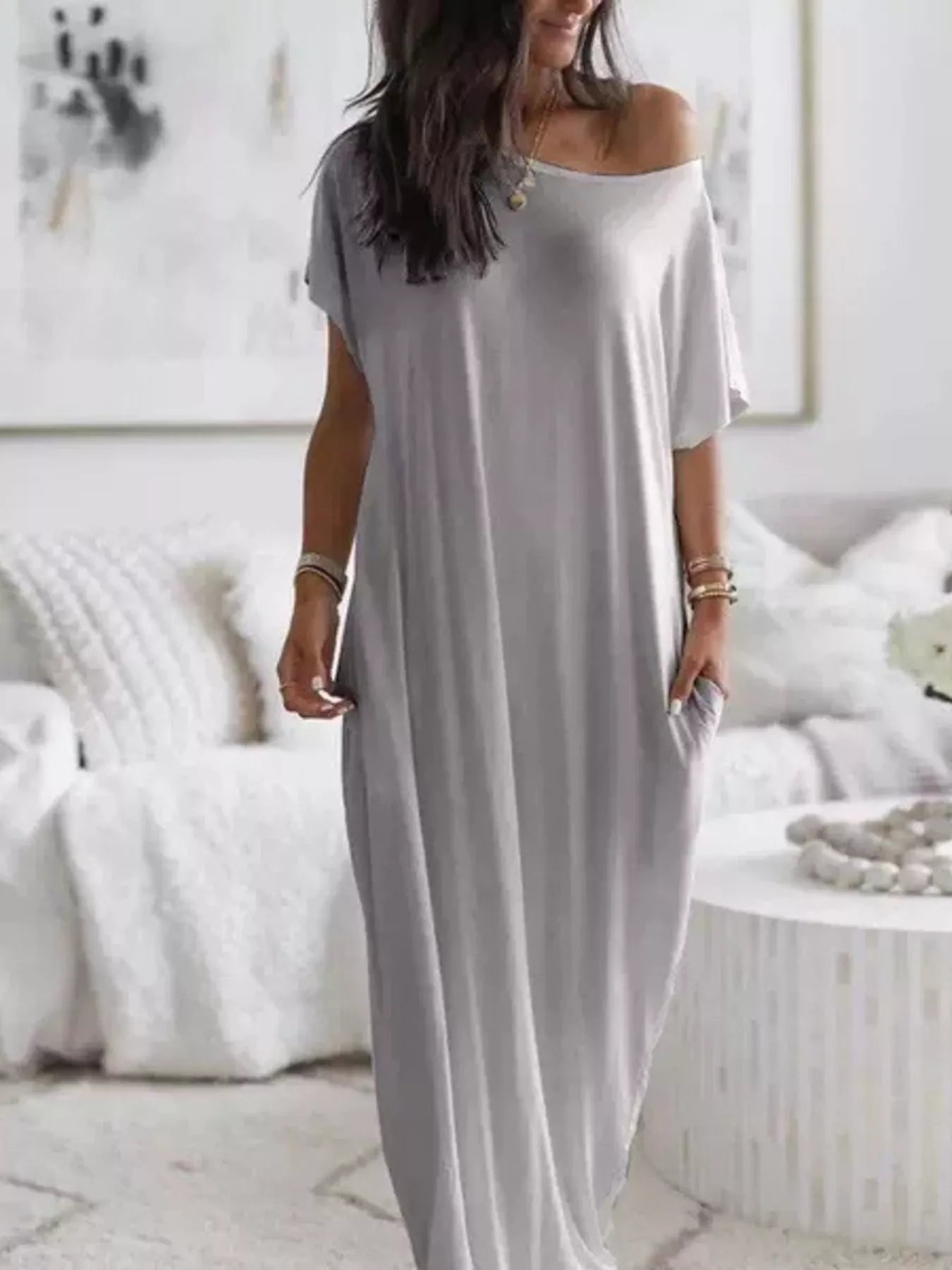 Woman wearing a long gray dress in a minimalistic room.
