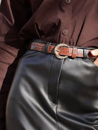 Person wearing a brown shirt and black leather pants with a brown belt.