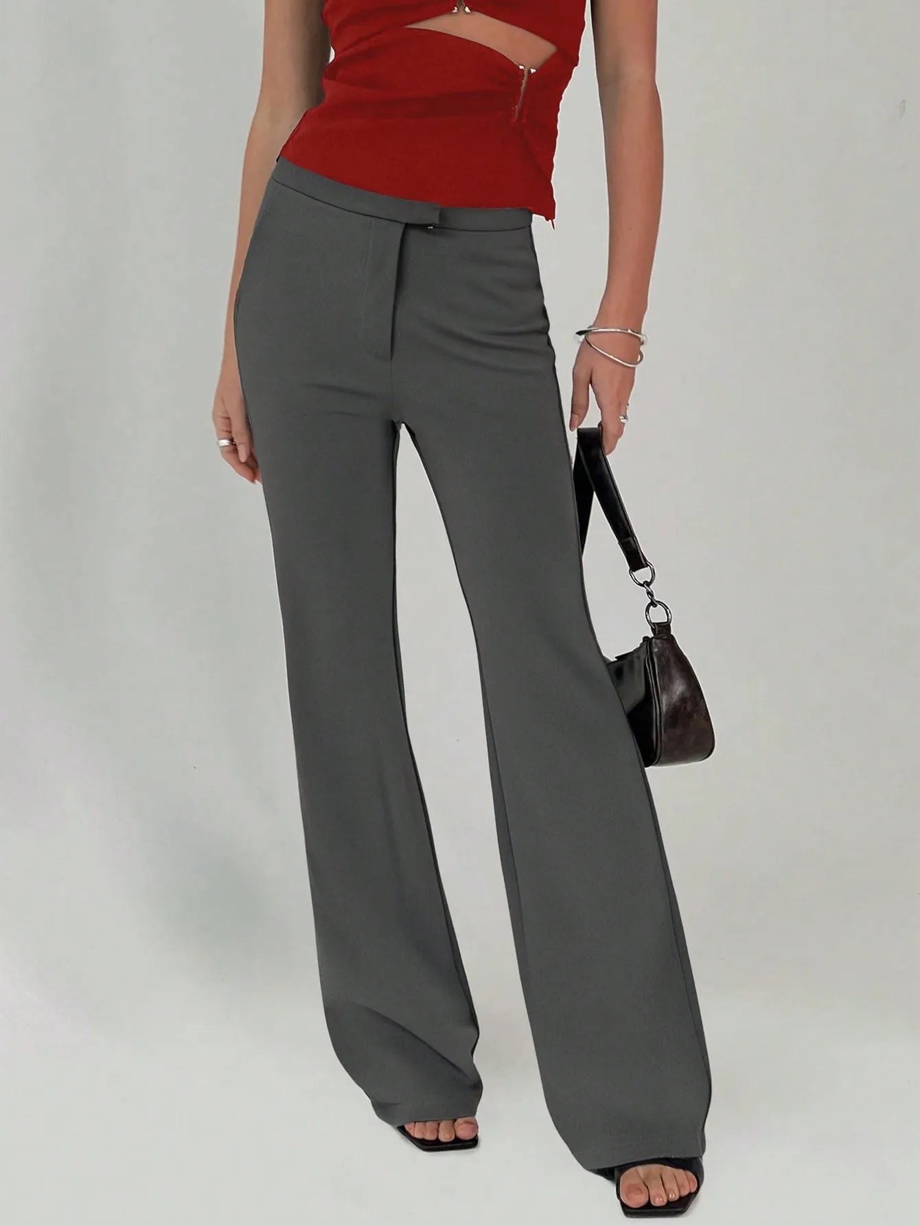 Person wearing gray wide-leg pants and a red top on a plain background