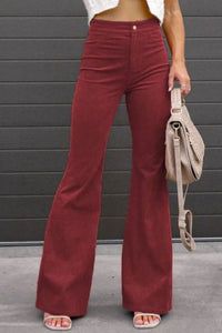 Person wearing maroon flared pants with a gray wall background