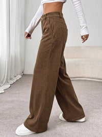 Brown wide-leg pants worn by a person in a minimal indoor setting