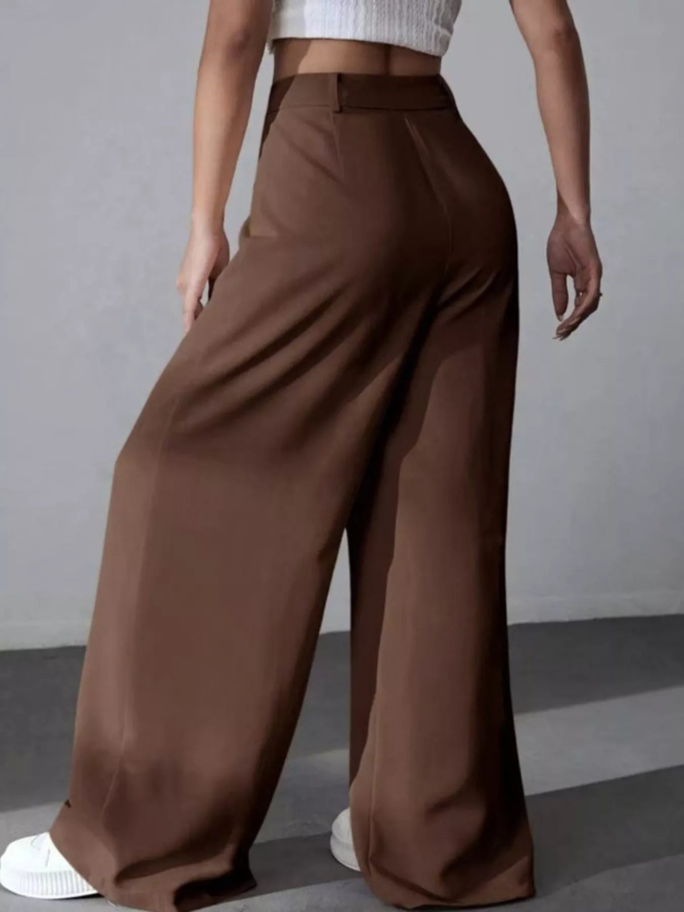 Brown wide-leg pants worn by a person on a gray background