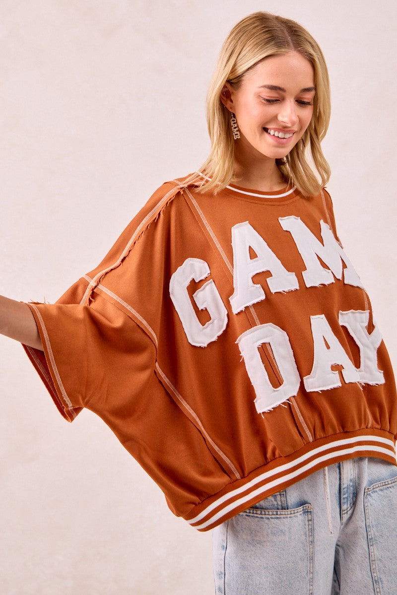 Person wearing a 'GAMEDAY' sweater with a plain background