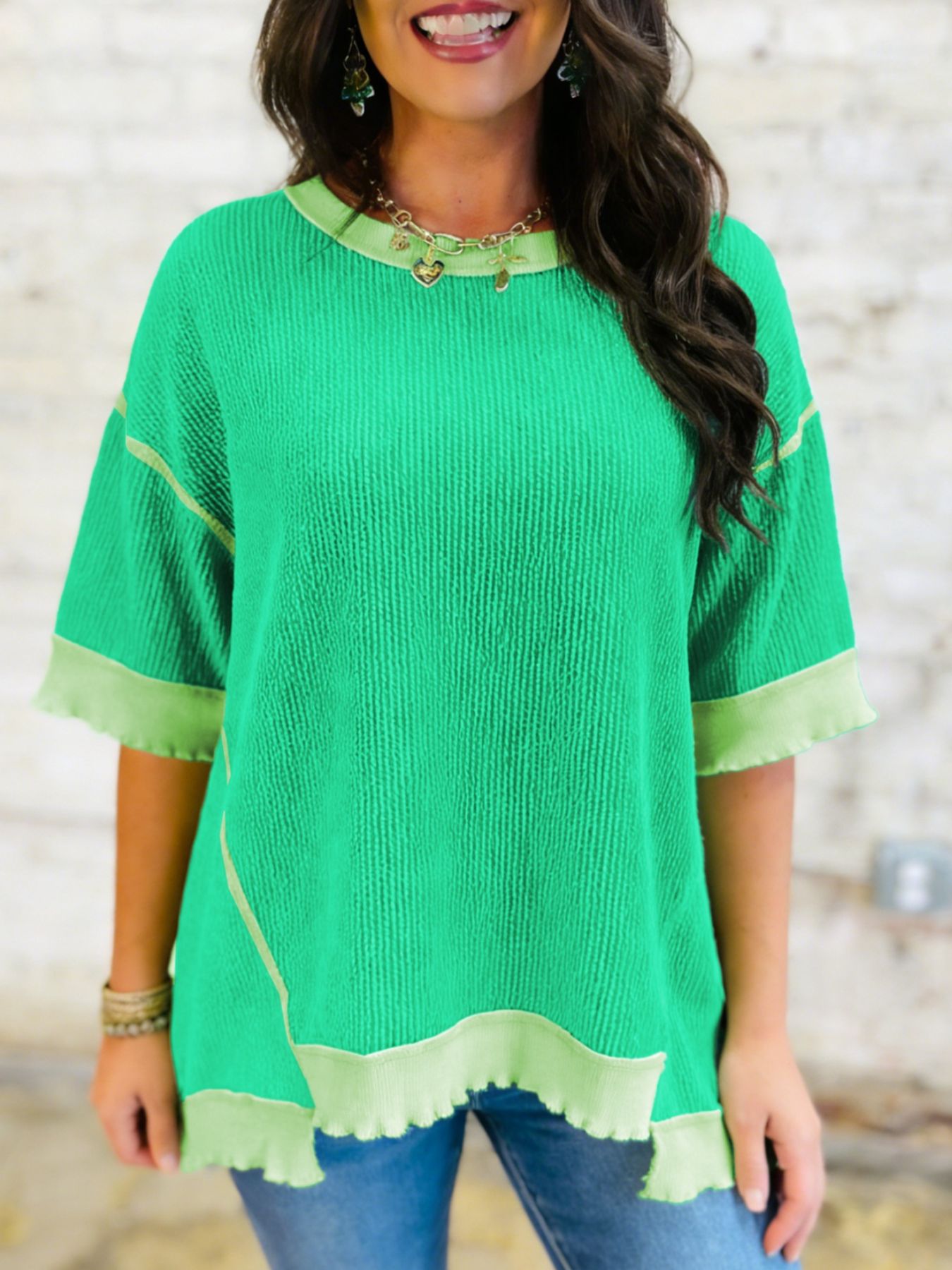 Woman wearing a green top with yellow trim against a neutral background
