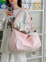 Person holding a pink bag with a cat plushie, standing in front of a white shelf.
