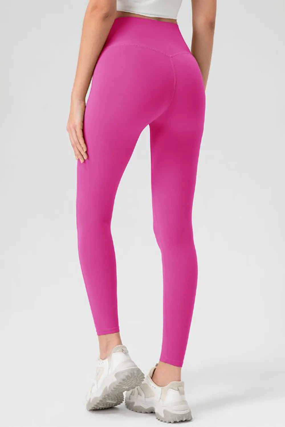 Person wearing bright pink leggings on a white background