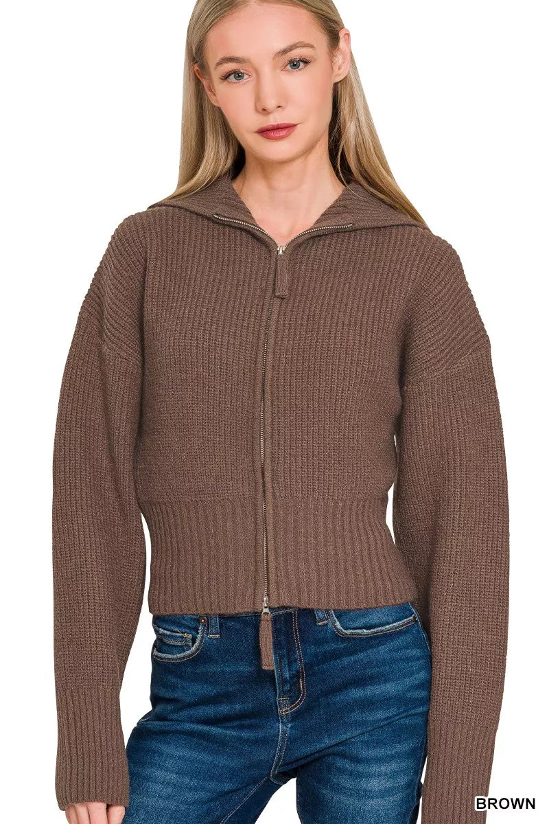 Woman wearing a brown zip-up hoodie with a plain background