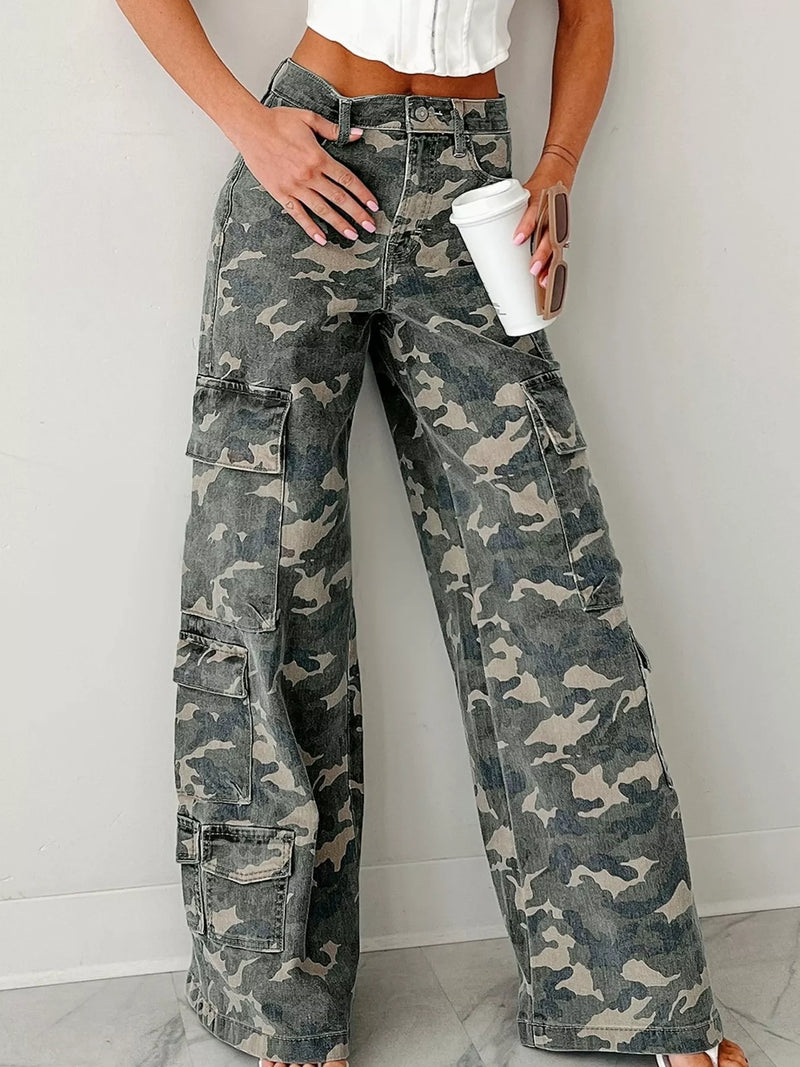 Person wearing camouflage cargo pants holding a white cup against a plain background