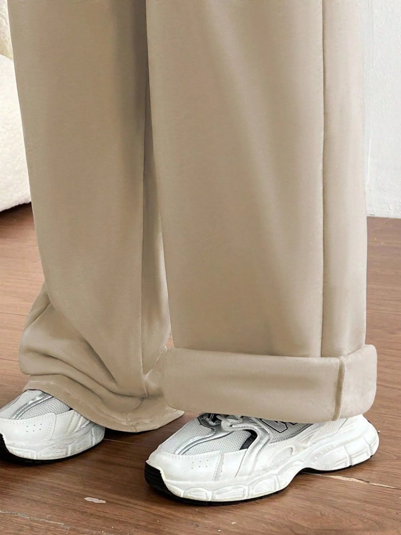 Beige pants with white sneakers on a wooden floor