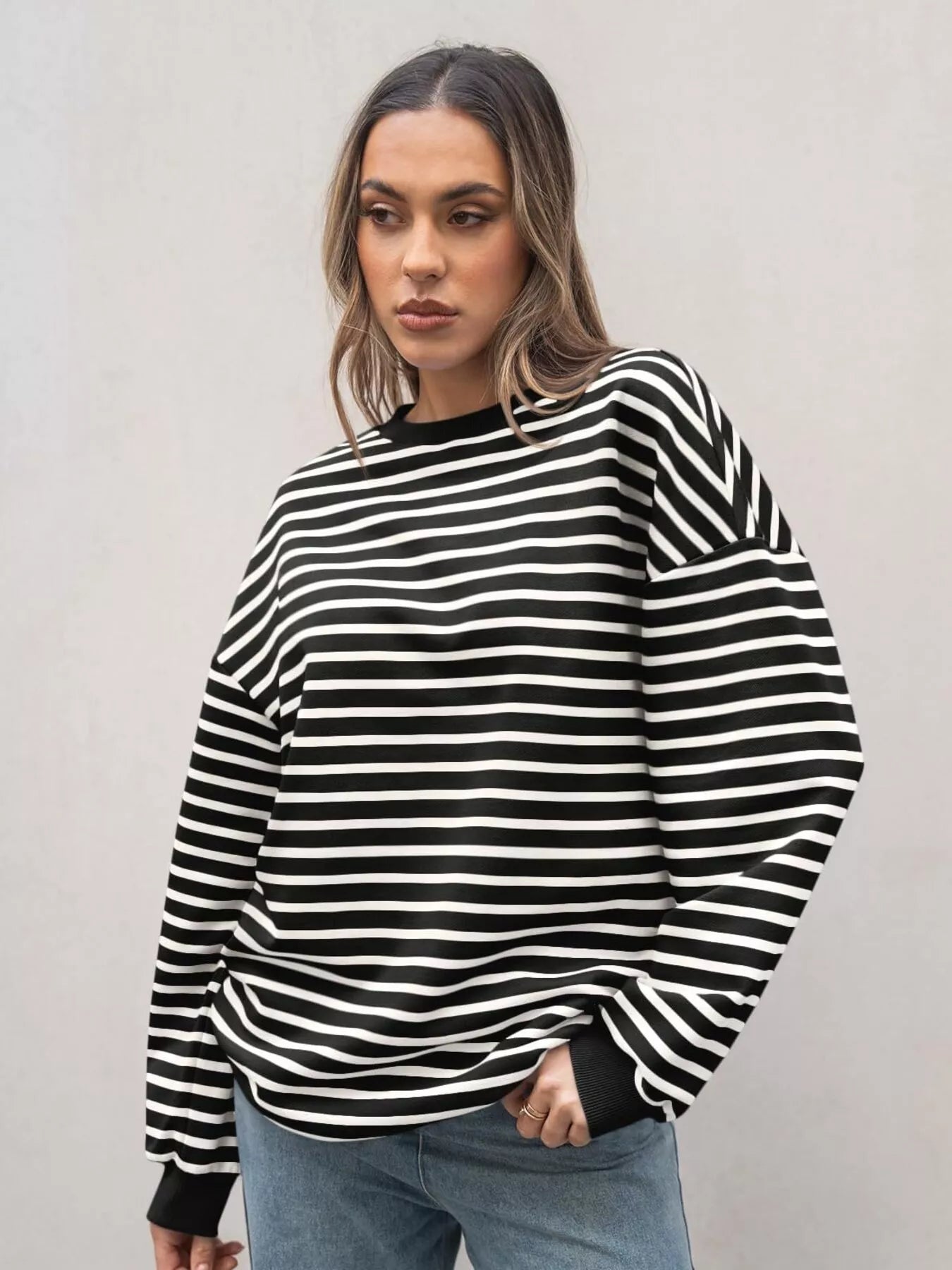 Woman wearing a black and white striped sweater against a plain background