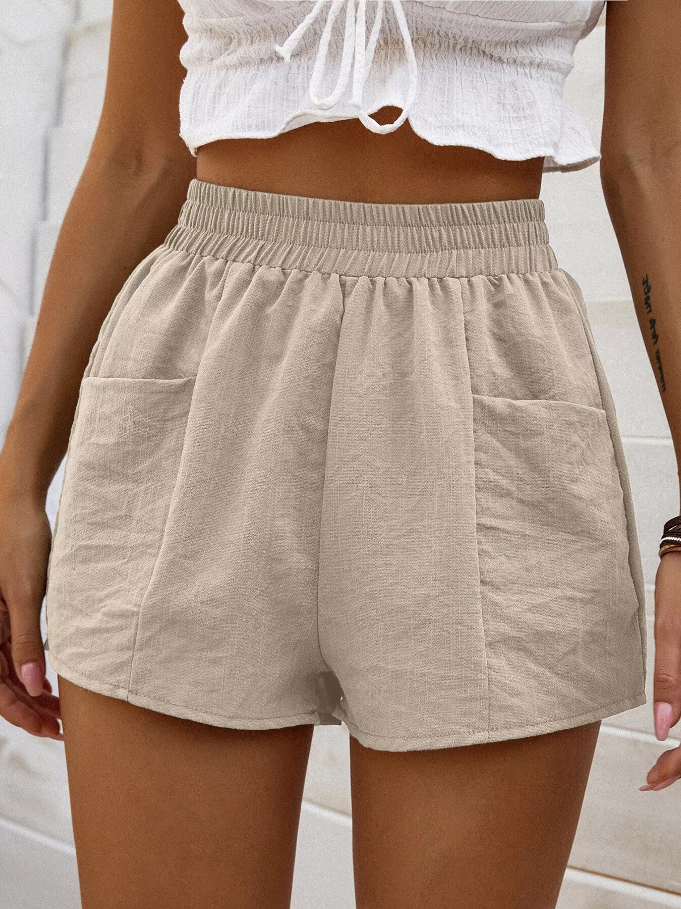 Beige shorts worn by a person with a white top against a light background