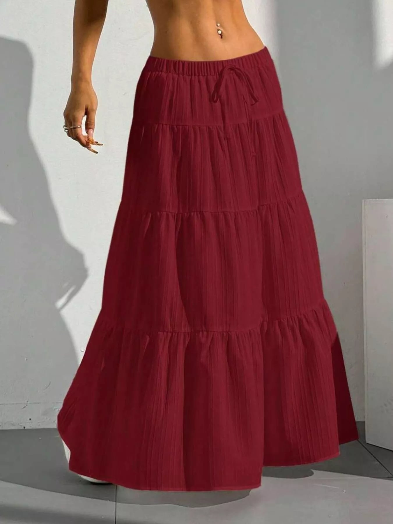 Red tiered skirt worn by a person against a white wall.